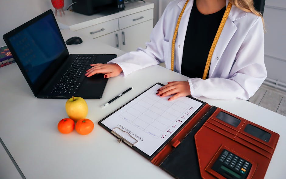 nutrition coach reviewing a meal plan on a laptop with healthy food on the desk