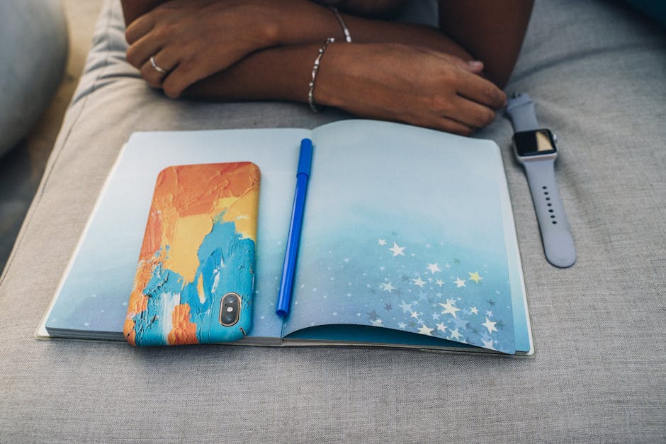 person writing in a journal next to a phone showing a coaching challenge daily prompt