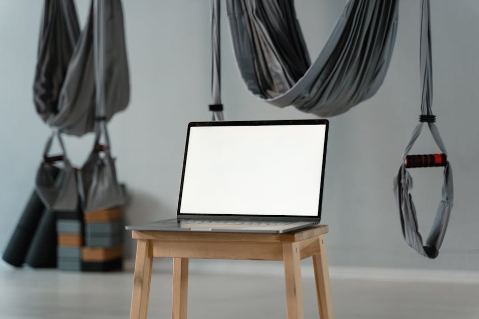 Fitness Influencer Passive Income in 2026: The 4-Layer Automated Revenue Stack 4 Minimalist yoga studio with aerial hammocks and blank laptop screen on a stool, ideal for diverse wellness themes.