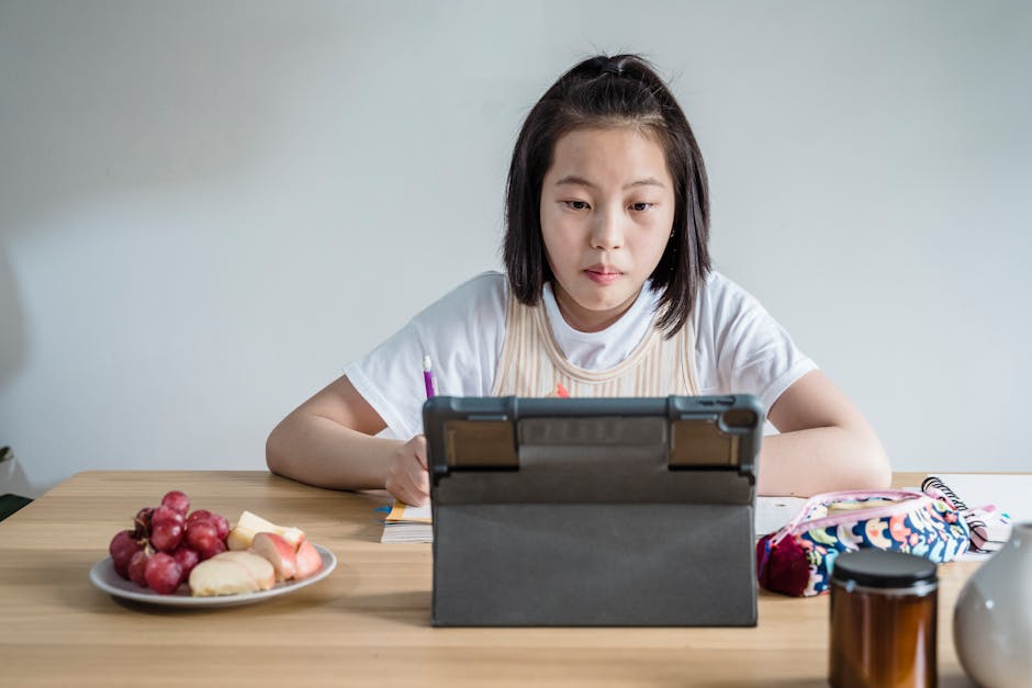 Person watching online class on tablet taking notes